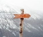 A wooden directional sign on top of a snowy mountain, advertising Prosper Spa.
